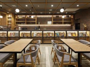 札幌LAMP LIGHT BOOKS HOTEL sapporo的餐厅设有木桌、椅子和柜台