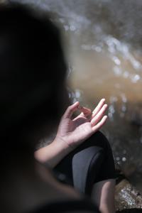 帕洋安Pramana Giri Kusuma的手放在水中坐在岩石上的人