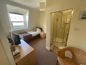 海斯廷斯亚历山大旅馆的一间带一张床和淋浴的浴室以及一张书桌