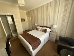 海斯廷斯亚历山大旅馆的配有一张床和一把椅子的酒店客房