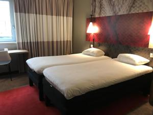 鲁昂ibis Rouen Centre Champ de Mars的配有白色床单的酒店客房内的两张床