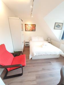 海牙Scheveningen Sea Side的卧室配有白色的床和红色椅子
