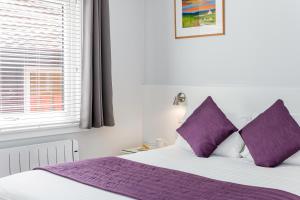 阿维莫尔高山自助式度假屋的一间卧室配有一张带紫色枕头的床和窗户。
