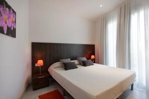 巴塞罗那勒科尔茨费萨租赁公寓的一间卧室配有一张带两盏灯的大型白色床。