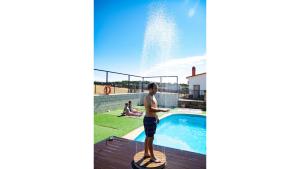 托雷洪厄尔卢比奥蒙福拉古乡村公寓的站在游泳池旁的桨板上的男孩