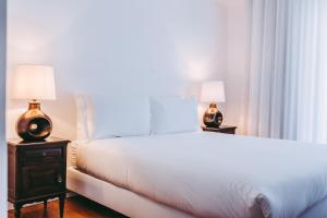 里斯本54 São Paulo - Exclusive Apartment Hotel的卧室配有一张白色大床和两盏灯。