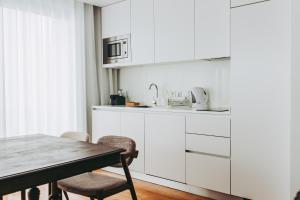 里斯本54 São Paulo - Exclusive Apartment Hotel的厨房配有白色橱柜和桌椅