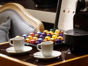 罗马马里奥德菲奥里37酒店的桌子上放两个咖啡杯和一个五颜六色的珠子托盘