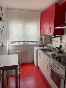 桑坦德Coqueto apartamento cerca de la playa的一间红色橱柜和红色地板的厨房