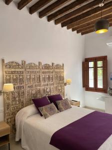 Fernán PérezMdina Casa Rural的一间卧室配有一张带紫色枕头的大床
