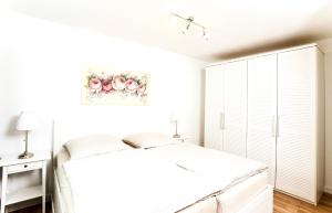 巴特塞森多夫Gästehaus Sam的白色的卧室,配有一张床和一幅鲜花画