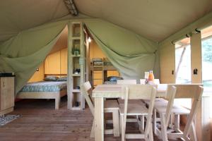Tardets-SorholusTENTE SAFARI Lodge FERME CARRIQUE的帐篷内的用餐室,配有桌椅