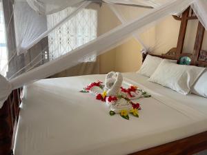 江比阿Visitor's Inn的一间卧室,床上放着鲜花