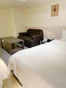 台北沃客商旅 - 成功馆的卧室配有一张白色的大床和一张沙发。