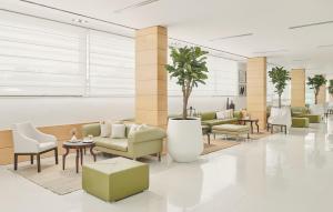 波尔蓝阳埃拉弗萨酒店的大堂配有沙发和椅子,并种植了棕榈树