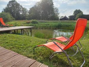 AnspokiZaķu muiža的两把椅子和一张池塘旁的野餐桌