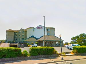 林肯市Siletz Bay Beachfront Hotel by OYO Lincoln City的停车场内有车辆的旅馆