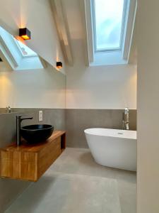 布伦瑞克“STADT-LAND-SCHEUNE” - luxuriös in alten Gemäuern的带浴缸、水槽和窗户的浴室
