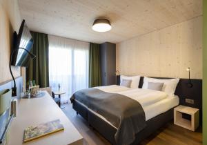 萨沃宁JUFA Hotel Savognin的酒店客房设有一张大床和一张书桌。