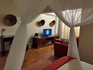 马普托Sundown Guest House Maputo的一间带床和电视的客厅