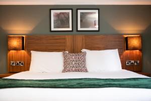 威布里治The Oatlands Chaser by Innkeeper's Collection的卧室配有一张墙上有两张照片的床。