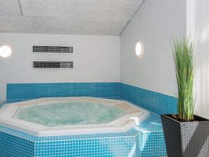 格莱斯堡12 person holiday home in Glesborg的浴室设有蓝色瓷砖,配有按摩浴缸。