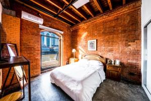 布宜诺斯艾利斯Madero Homes的砖墙卧室,配有一张床和一个窗户