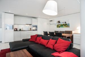 ChamCITY STAY - Zugerstrasse的客厅配有黑色沙发和红色枕头