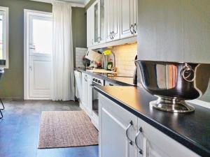 Hallstavik5 person holiday home in HALLSTAVIK的厨房配有白色橱柜和黑色台面
