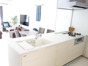 北谷町サンライン北谷コンドミニアムリゾート的一间带水槽的白色厨房和一个客厅