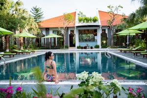 宁平Bai Dinh Riverside Resort & Spa的坐在游泳池旁的身着泳衣的女人