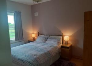 KinnittyPrimrose Cottage的一间卧室配有一张床和两张台灯。
