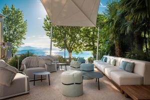 代森扎诺-德尔加达Villa Rosa Hotel Desenzano的一个带沙发和桌子的庭院和一个大伞