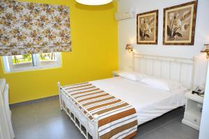 蒂加基Kos Palace的卧室配有白色的床和黄色的墙壁