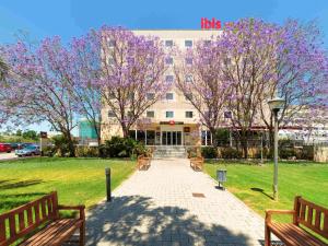 穆尔西亚宜必思穆尔西亚酒店的一座有两长椅和紫色花卉的树的建筑
