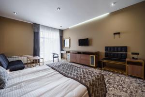 捷尔诺波尔Rudison Hotel & Restaurant的配有一张床和一台平面电视的酒店客房