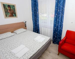 格但斯克Pokoje Gościnne 2的一间卧室配有一张床和一张红色椅子