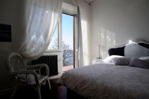 蒙蒂菲阿斯科尼Il Caminetto Montefiascone的一间卧室设有一张床、一个窗口和一把椅子