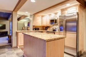 帕克城Empire Duplex的厨房配有木制橱柜和不锈钢冰箱。