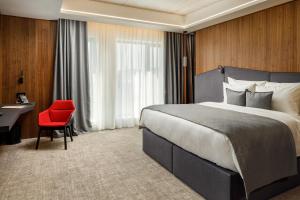 布拉索夫Qosmo Brasov Hotel的酒店客房设有一张大床和一张红色椅子。