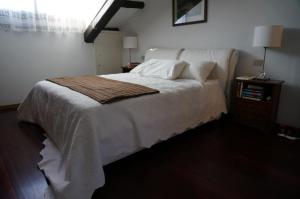 威尼斯丽都Stylish Penthouse Apartment in Venice Lido, 10 minutes from Saint Marks Square的卧室铺有木地板,配有白色的床。