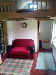 TuamgraneyCastaway Cabin的一个小房间里一张红色的沙发,配以时钟