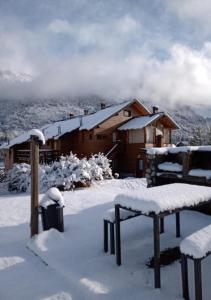 圣卡洛斯-德巴里洛切Punto Bariloche的小屋前面有长凳,被雪覆盖