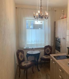 比尔扎伊Arbatinės apartamentai的厨房配有桌子和两把椅子,设有窗户。