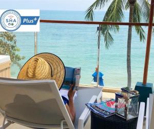 拉迈Royal Beach Boutique Resort & Spa Koh Samui - SHA Extra Plus的坐在椅子上,在沙滩上使用笔记本电脑的人