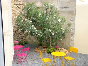 罗什福尔Bleu Soleil Rochefort 3 étoiles的花园里的几张五颜六色的桌子和椅子