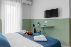 索伦托Sorrento Colors&Suites的一间卧室配有一张带毛巾和帽子的床