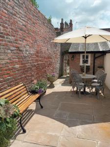 格拉斯顿伯里Delighful self catering in the heart of Glastonbury的庭院设有木凳和遮阳伞。