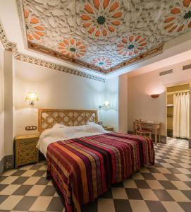 塞维利亚塞维利亚国王寝宫酒店的一间卧室配有一张带花卉天花板的床