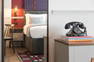 卡迪夫加的夫靛蓝酒店的一间卧室配有一张床,桌子上配有一部电话